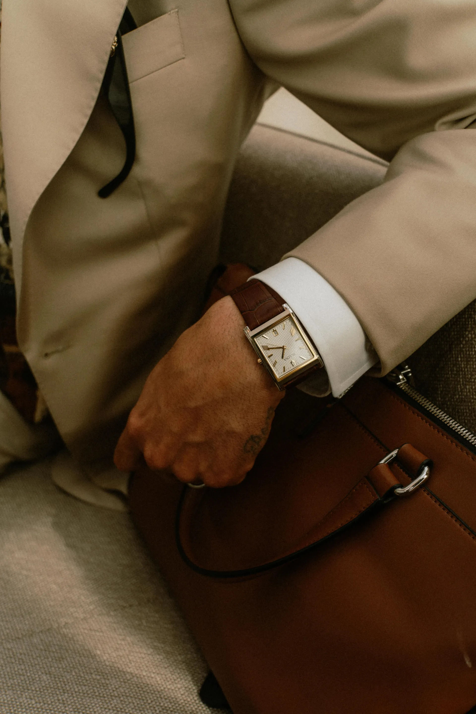 Business suit detail with leather watch and brown leather bag