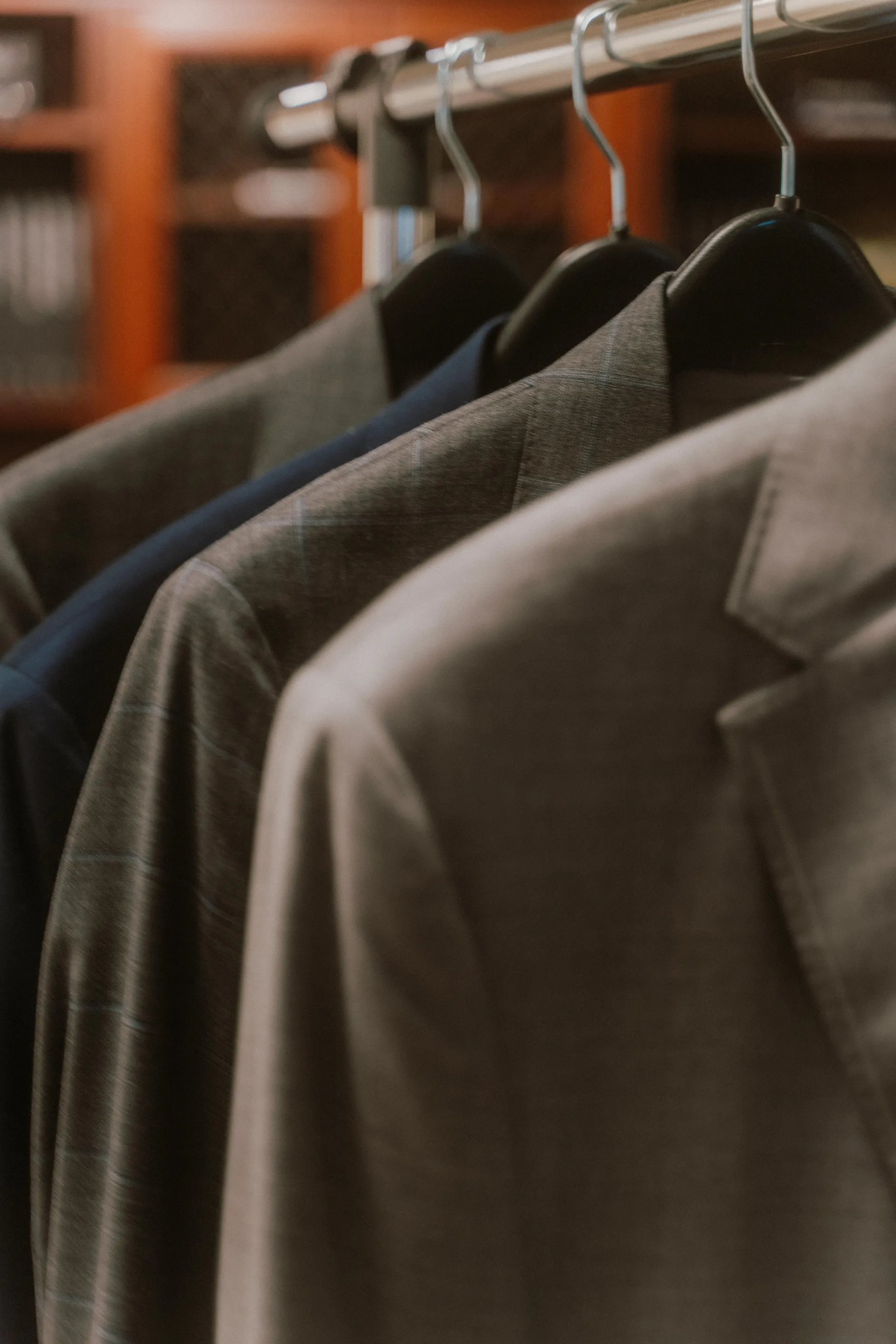 Row of finished bespoke suits in the Fino Los Gatos studio